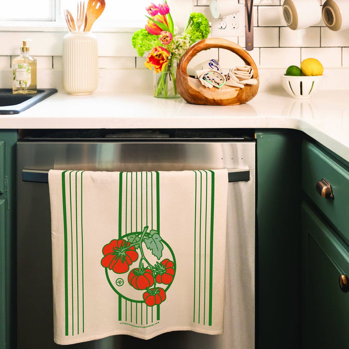 Kitchen scene with a dish towel hanging on a stove, green cabinets, and various kitchen items.