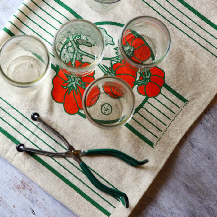 Four small glasses on a decorative towel with tomato design