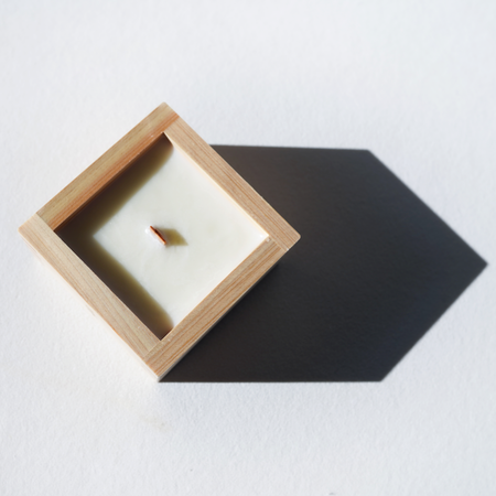 Candle in a wooden holder on a white surface