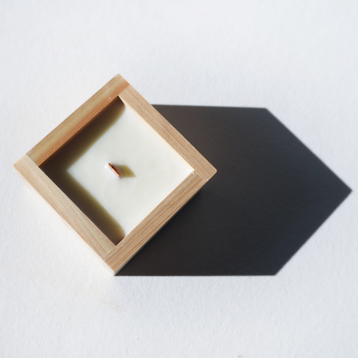 Candle in a wooden holder on a white surface